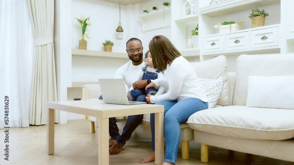 Happy african family parents and little children enjoy using computer laptop together sit on sofa, technology addicted couple with kids having fun at home Happy african family parents and little children enjoy using computer laptop together sit on sofa, technology addicted couple with kids having fun at home