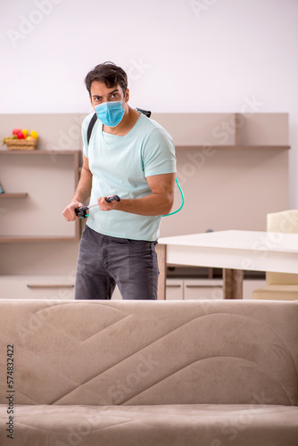 Young male contractor doing pest control at home