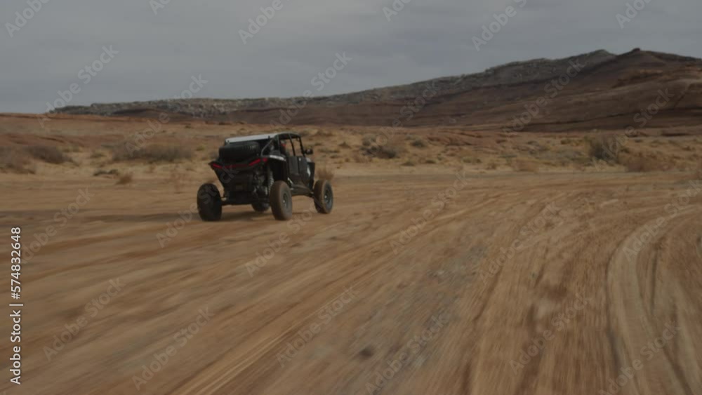 Tracking shot behind UTV driving in sunny Utah desert landscape in sand wash