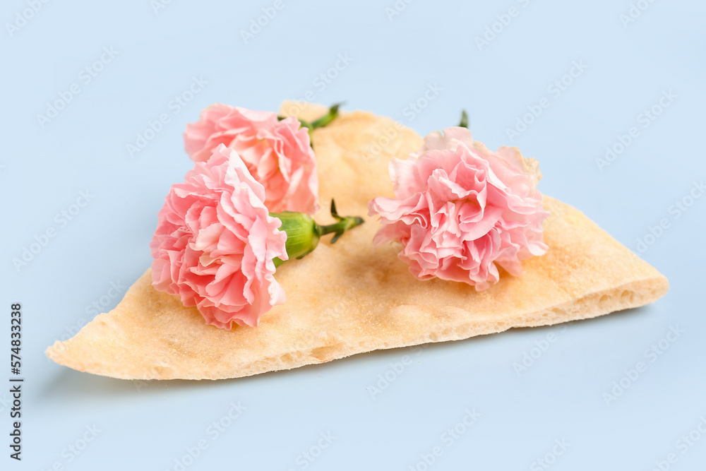 Slice of pizza with beautiful carnation flowers on light background Slice of pizza with beautiful carnation flowers on light background