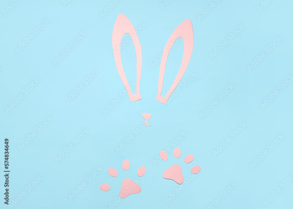 Composition with paper bunny ears, nose and paws on color background