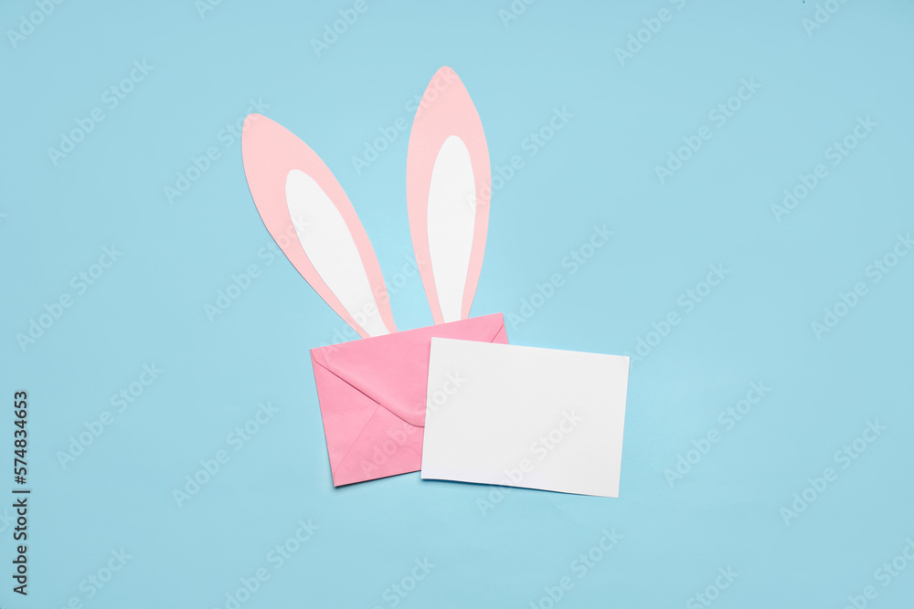 Composition with blank card, envelope and paper bunny ears on color background