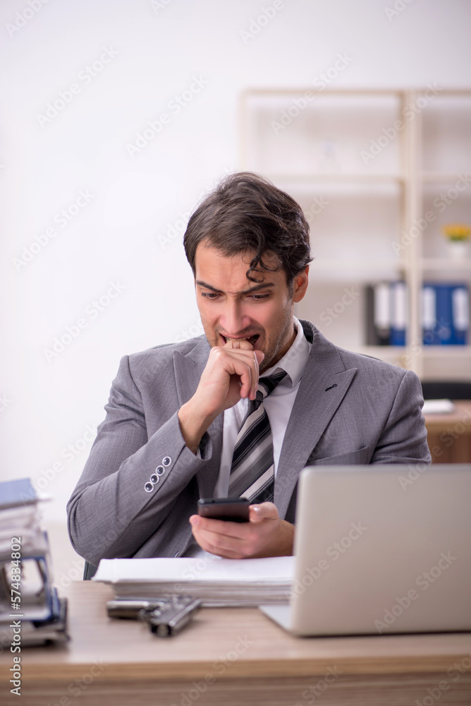 Young male employee unhappy with excessive work in the office Young male employee unhappy with excessive work in the office