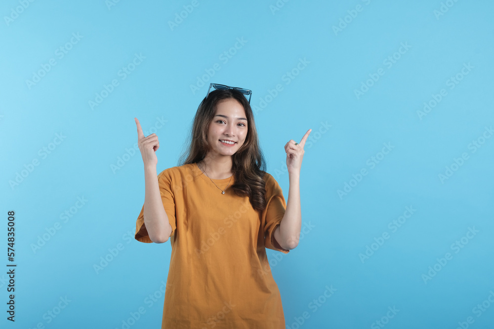 Asian young female using a sunglasses, gesture with her hands pointing to empty space on blue background Asian young female using a sunglasses, gesture with her hands pointing to empty space on blue background