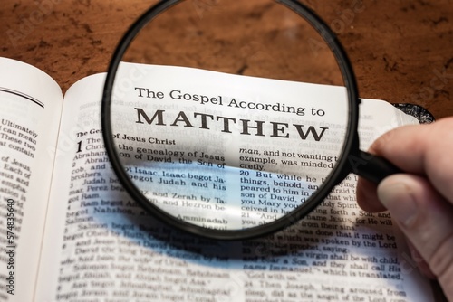 Fotografija title page book of Matthew close up using magnifying glass in the bible for fait