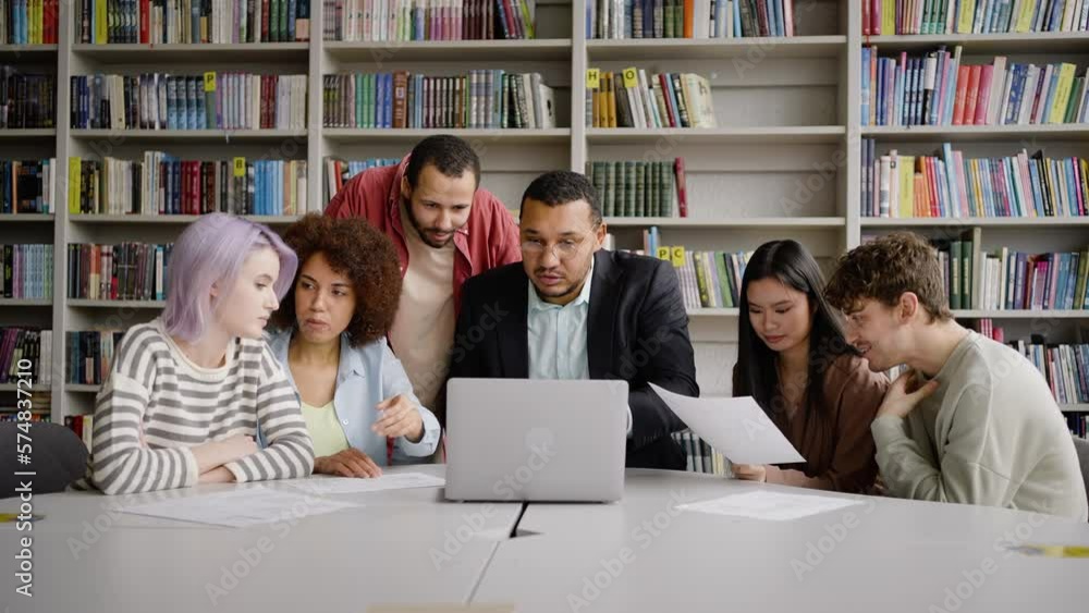 African male professor giving consultation to university graduate students, using laptop in library African male professor giving consultation to university graduate students, using laptop in library