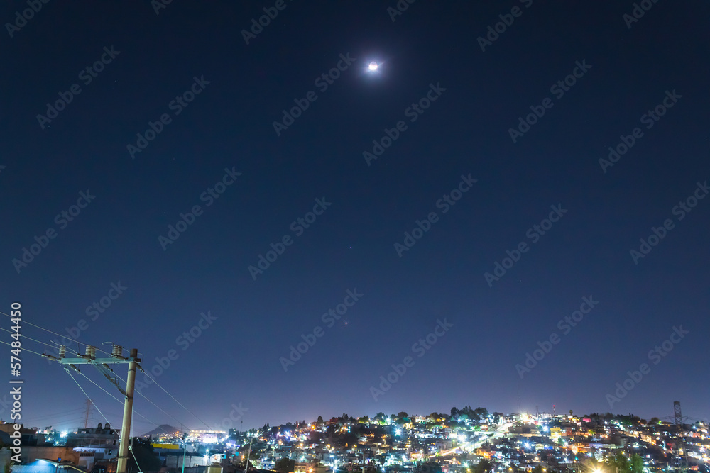 Fototapeta premium alignment of planets jupiter and venus, and the crescent moon in february 2023, planetary parade with city in the background 