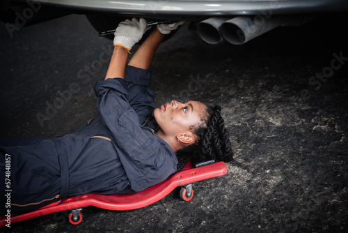 Auto mechanic are examining and performing maintenance beneath a vehicle at garage. Car repair and maintenanc concept. photo