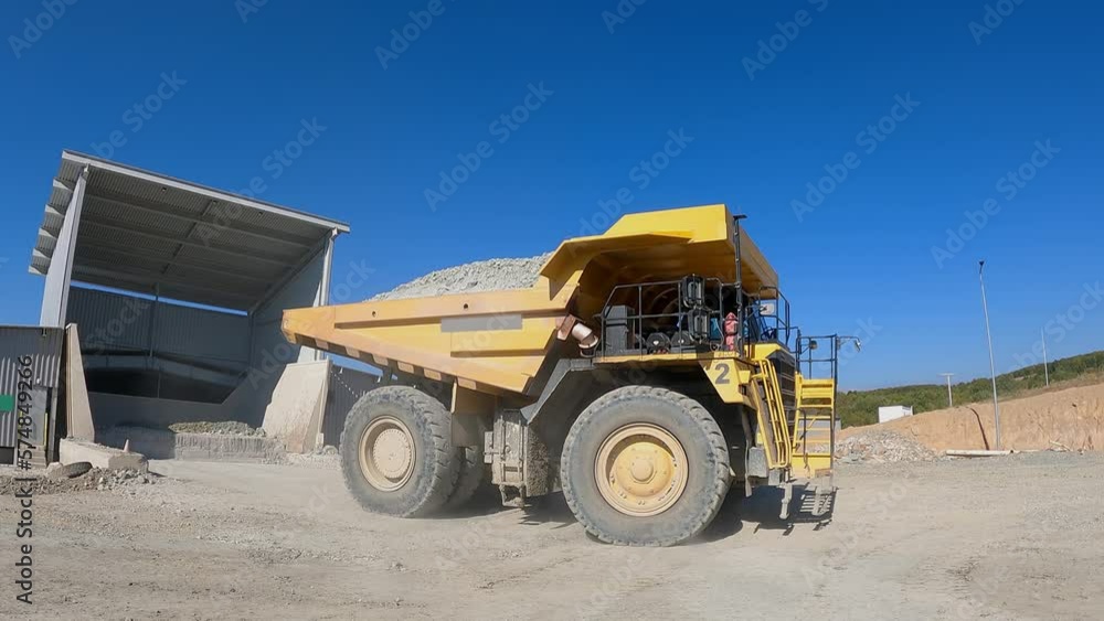 Big yellow mining truck at work site unloading ore in production facility, slow motion Big yellow mining truck at work site unloading ore in production facility, slow motion