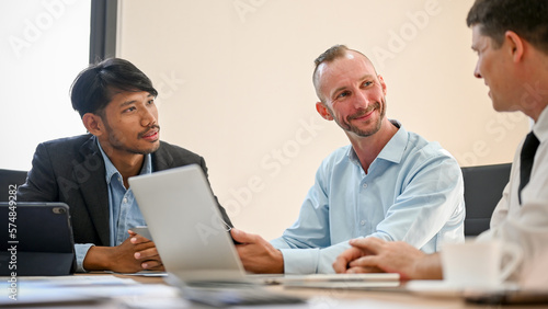 Cheerful Caucasian and Asian businessmen having a meeting with a financial consultant