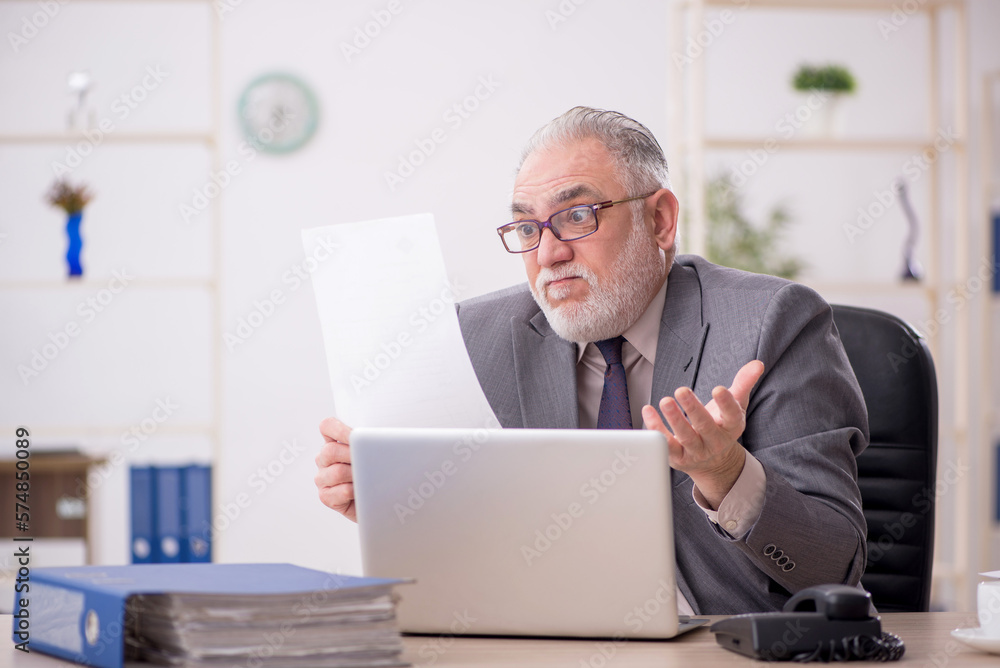 Old male employee working in the office Old male employee working in the office