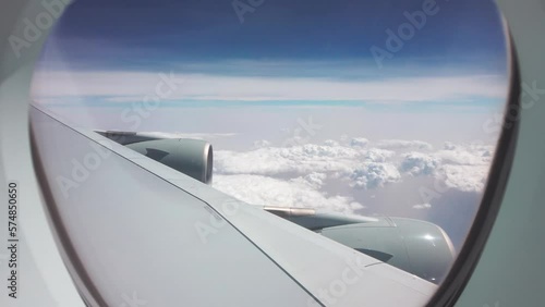 Large plane fly over flufy clouds on sunny day. View from passenger window to wing and two engines photo