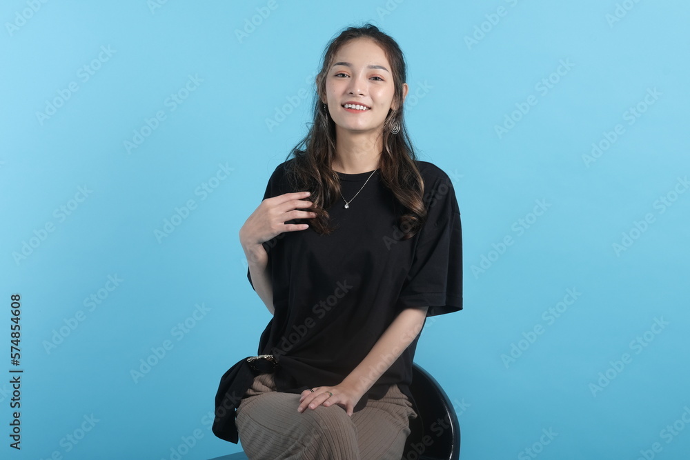 Asian young woman poses to camera wearing black t-shirt on blue background Asian young woman poses to camera wearing black t-shirt on blue background