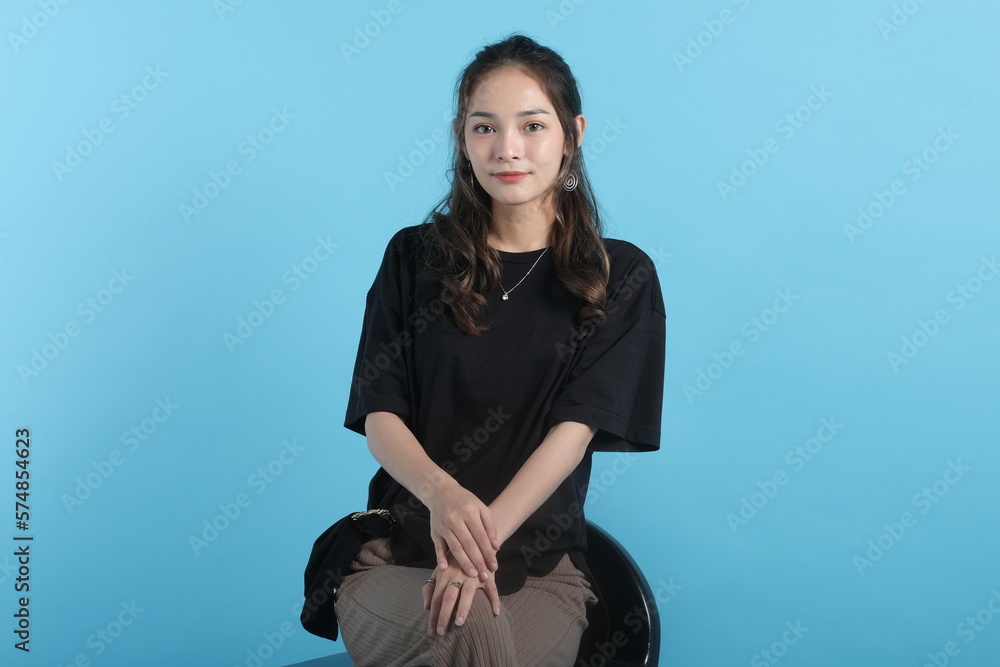 Asian young woman poses to camera wearing black t-shirt on blue background Asian young woman poses to camera wearing black t-shirt on blue background
