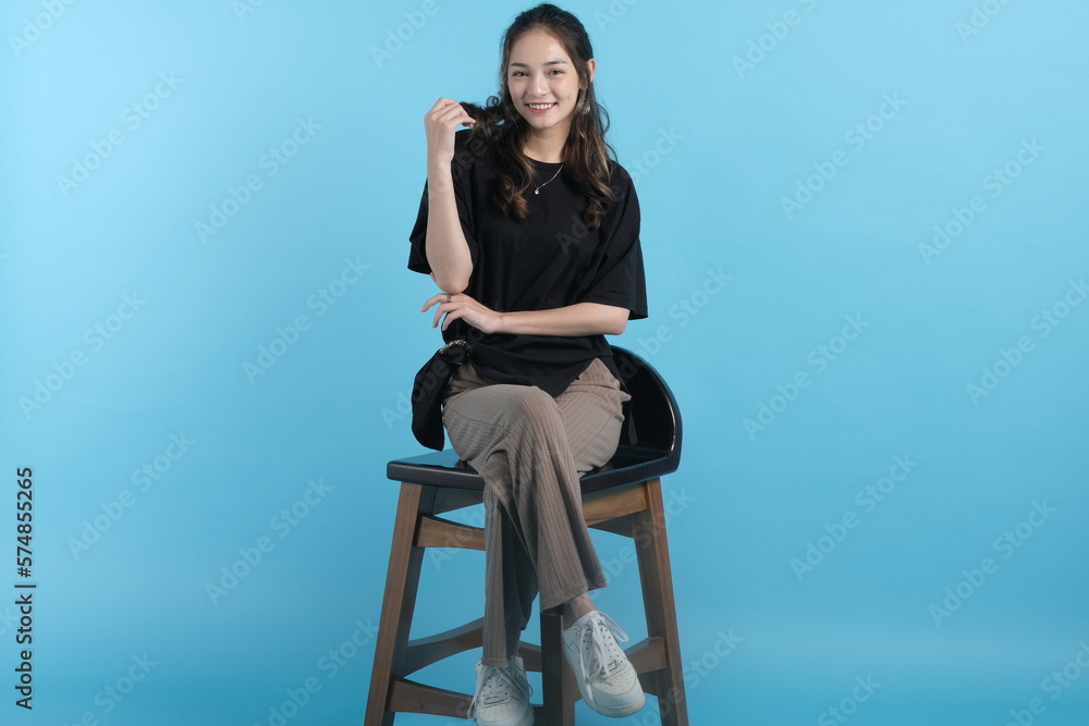 Asian young woman poses to camera wearing black t-shirt on blue background Asian young woman poses to camera wearing black t-shirt on blue background