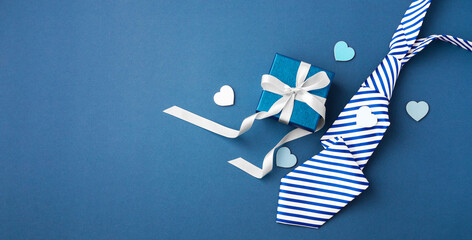 Gift box with white ribbon bow and tie on blue background, happy fathers day concept