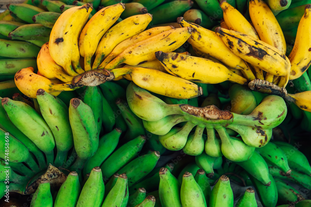 Fruit background of green bananas and yellow oranges and bananas on the market in Asia