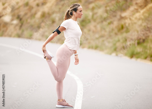 Runner, leg stretch and woman in a road with music for fitness, cardio and mindset preparation. Girk, stretching and nrunning in nature with podcast, radio or wellness motivation track for workout photo