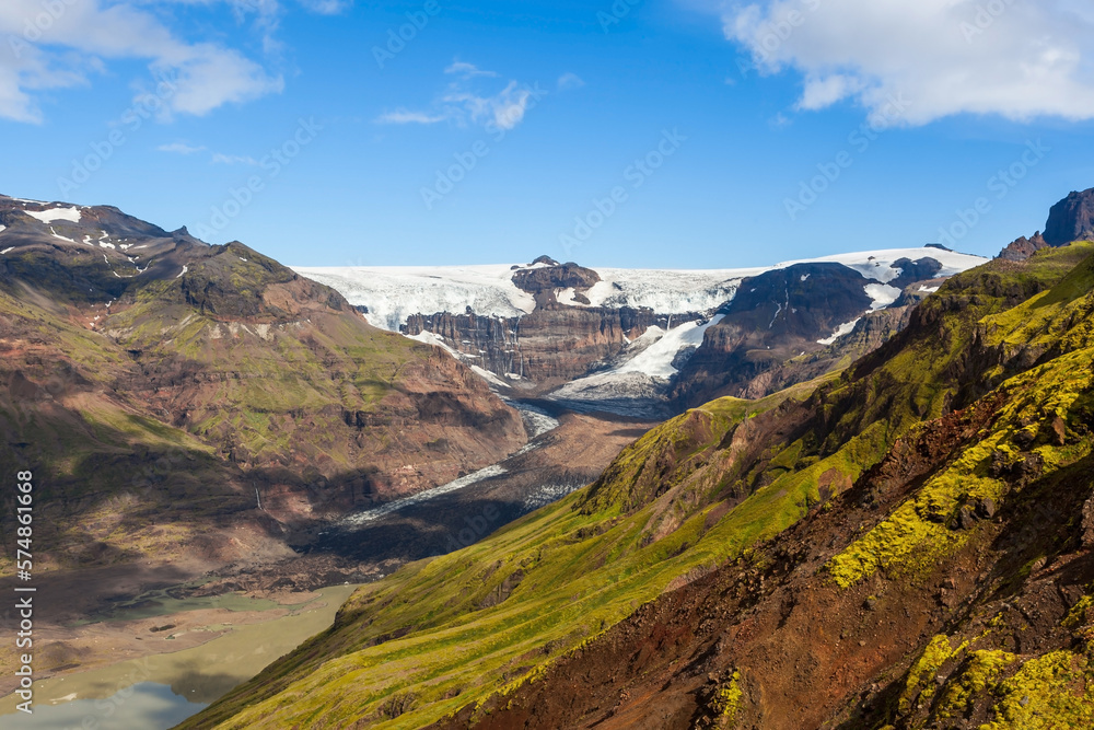 Skaftafel national park. Southern Iceland. Beautiful landscape of a white snowy mountain glacier coming down between two rocky slopes on a sunny day.