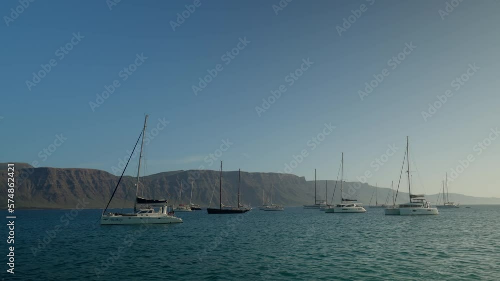 Anchored sailboats at a bay in La Graciosa, Lanzarote during midday with a cloudless sky Anchored sailboats at a bay in La Graciosa, Lanzarote during midday with a cloudless sky