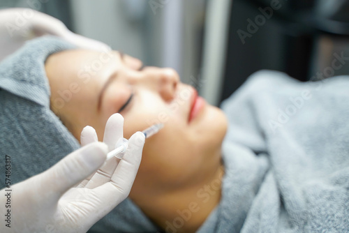 Closeup hands of beauty doctor in medical grove holding beauty skin syringe injecting the customer's face. Beauty skin concept