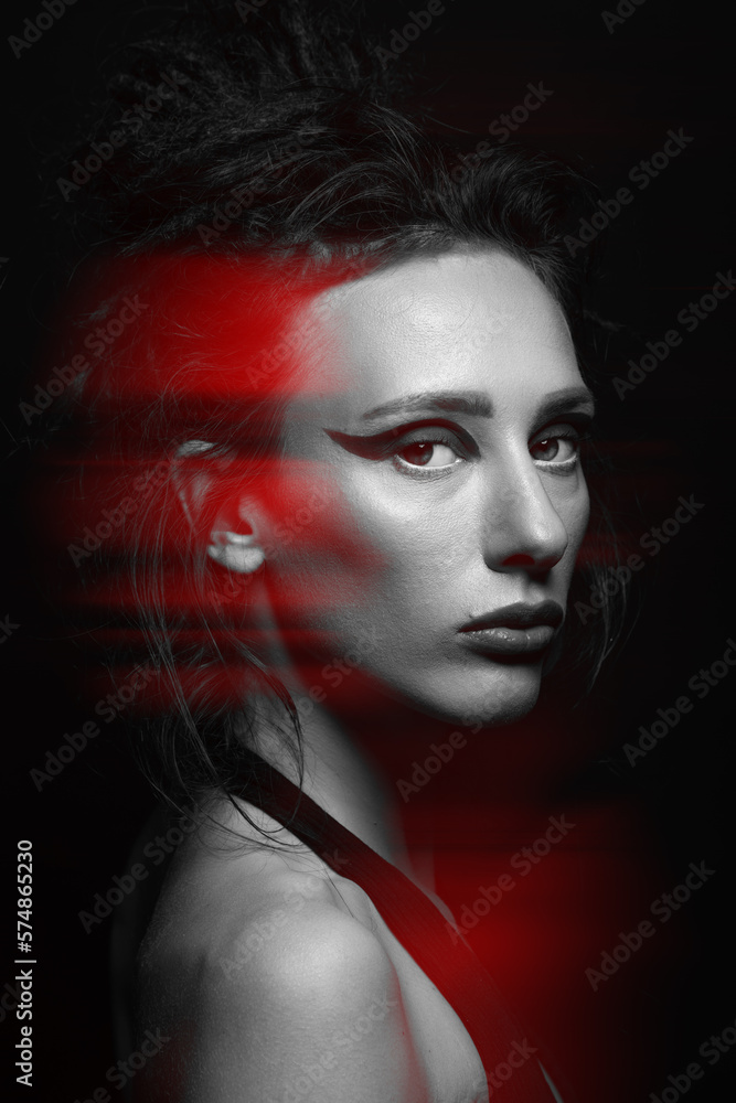 Studio portrait of beautiful woman in red color split effect. Model with eye shadows, long and dark dreadlocks hair looking at camera with seductive look. Futuristic looking style