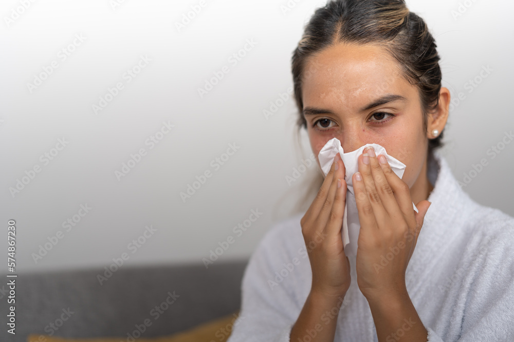 Young lady, covering and wiping her nose with a piece of tissue paper after sneezing Young lady, covering and wiping her nose with a piece of tissue paper after sneezing