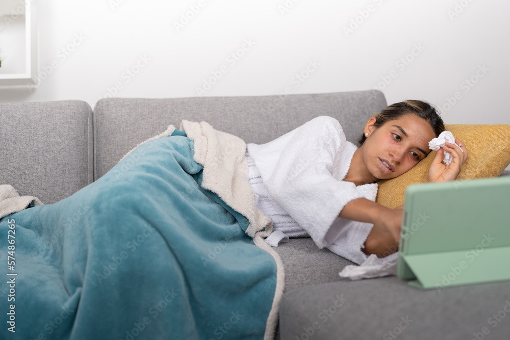 Young woman with flu and mucus, watching videos on digital tablet Young woman with flu and mucus, watching videos on digital tablet
