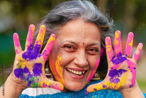 Indian senior woman playing colors and celebrating holi festival.