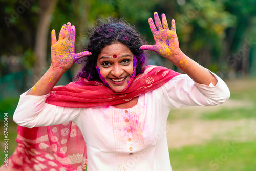 Indian woman playing colors and giving expression while celebrating holi festival.
