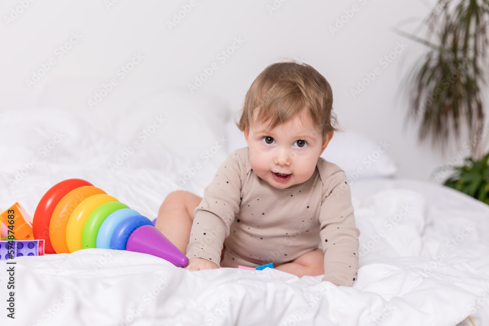 cute baby playing with colorful toys on bed, banner, space for text cute baby playing with colorful toys on bed, banner, space for text