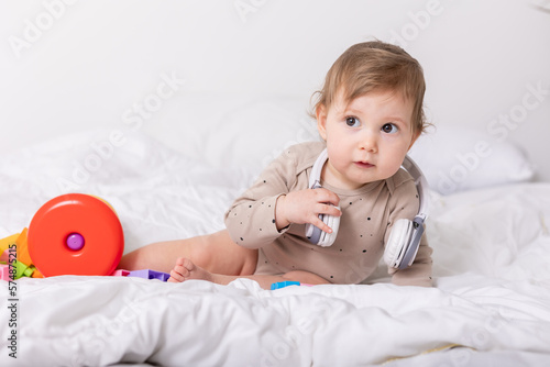 cute baby playing with colorful toys and headphones on blanket, banner, space for text