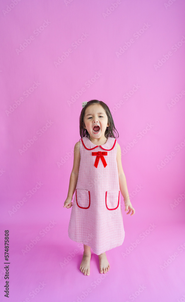 Pretty little girl standing in front of pink backdrop and shouting loud. Pretty little girl standing in front of pink backdrop and shouting loud.