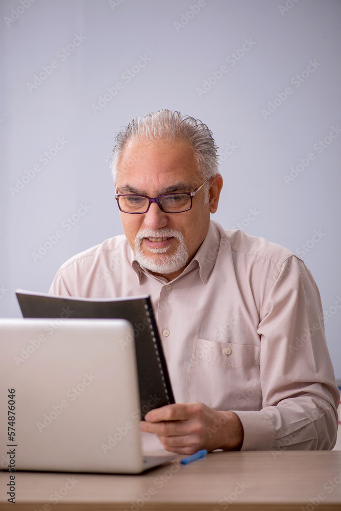 Old male teacher in front of whiteboard