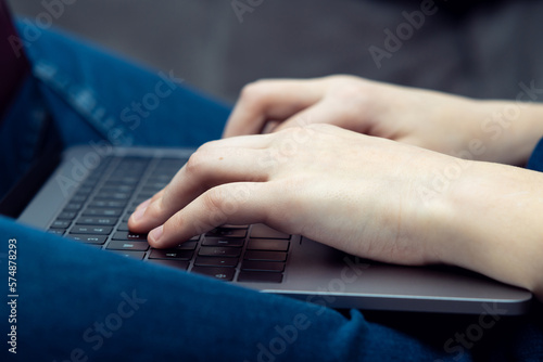 Digital laptop computer on male legs, side view closeup. Business man typing on keyboard of portable modern notebook.