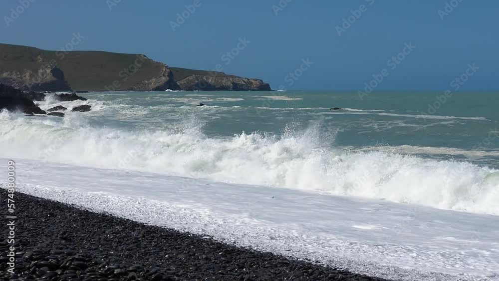 Waves crash onto stony beach on a clear summer's day - Birdlings Flat Beach (New Zealand) Waves crash onto stony beach on a clear summer's day - Birdlings Flat Beach (New Zealand)