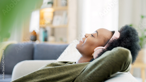 Canvastavla Young woman listening to music while relaxing on a sofa at home