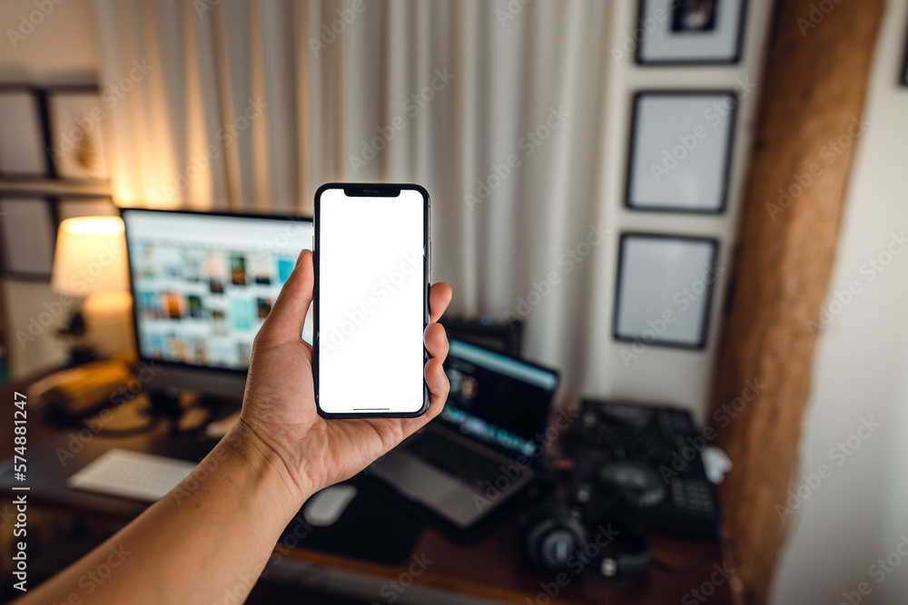 hand holding smartphone with blank screen in home desk hand holding smartphone with blank screen in home desk