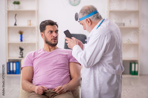 Young male patient visiting old male doctor otologist