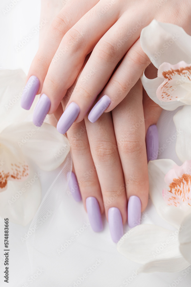 Girl's hands with delicate purple manicure and orchid flowers