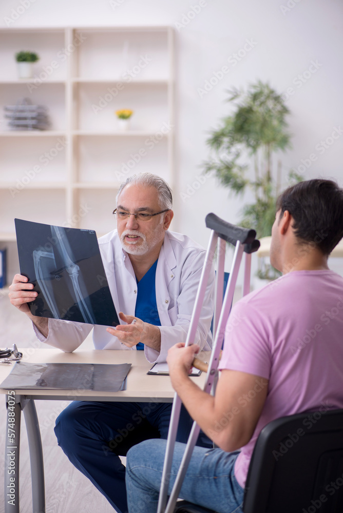 Young leg injured patient visiting old male doctor radiologist Young leg injured patient visiting old male doctor radiologist