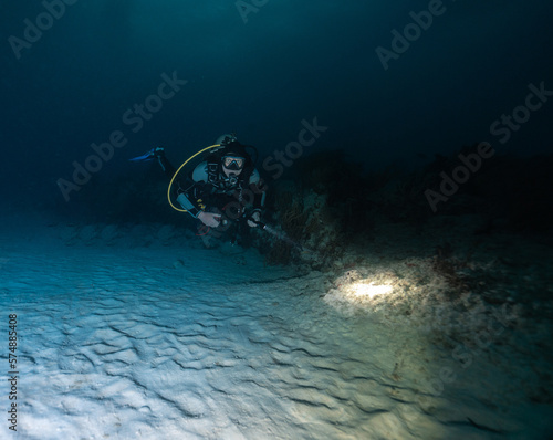 male scuba diver posing in front of coral reef in a night dive
