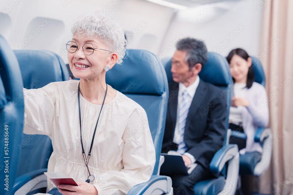 機内エンターテイメントを楽しむ高齢の女性 機内エンターテイメントを楽しむ高齢の女性