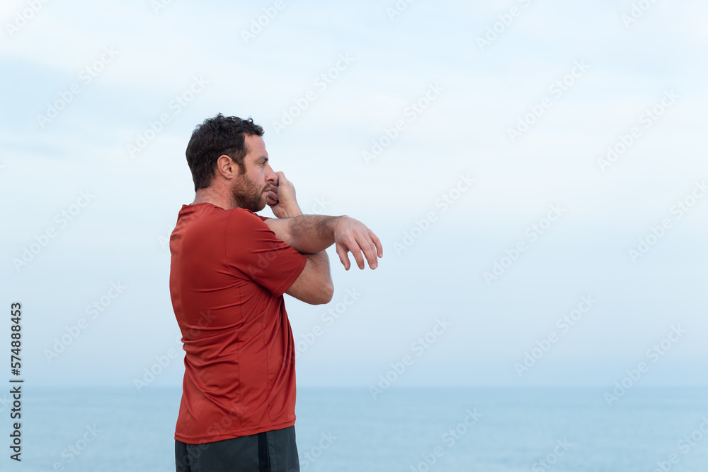 Side view of a man stretching his shoulders in front of the sea. Side view of a man stretching his shoulders in front of the sea.