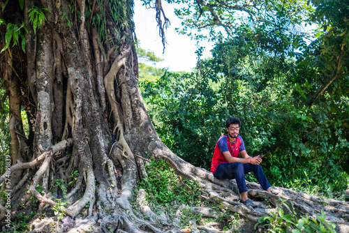 South asian young traveler taking rest under a large banyan tree 