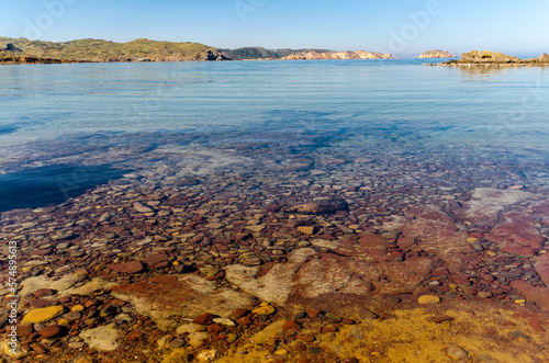 Cala virgen del norte de Menorca con aguas transparentes, donde se aprecia el fondo marino 