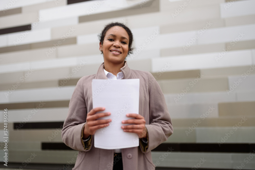 African american woman manager in business clothes holding documents. Happy business woman on the street after a successful meeting.Concept of management, time planning.