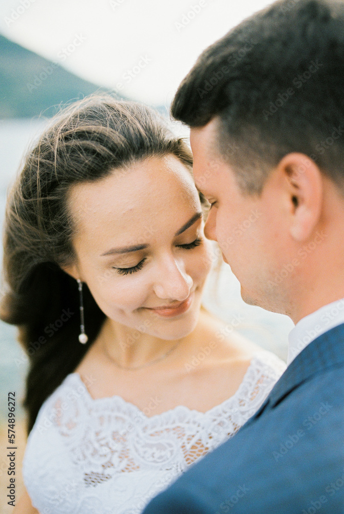 Groom tilted his face to the face of the smiling bride. Portrait