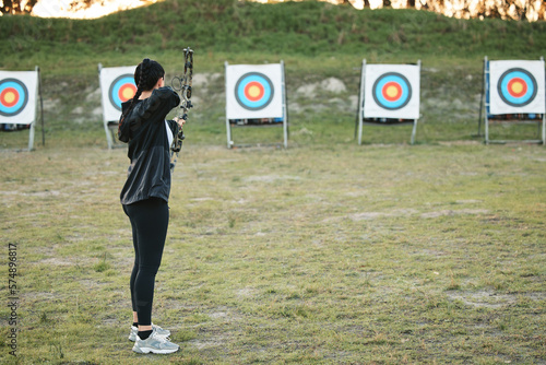 Sports, archery target and bow and arrow training for archer competition, athlete challenge or girl field practice. Shooting, objective and competitive woman focus on precision, aim or outdoor mockup photo