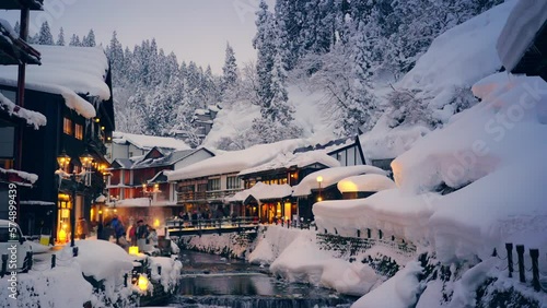 4K Landscape of Beautiful nature in winter season. Ginzan Onsen area  in Yamagata prefecture, Japan covered in snow and people tourist walking down street in snowing day on winter holiday vacation.